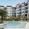  Two Bedroom Luxury Apartments in Maitland FL - Perla Gem Lake - Resort-Style Pool with Lounge Seating, Palm Trees, and White Building Exterior in the Background